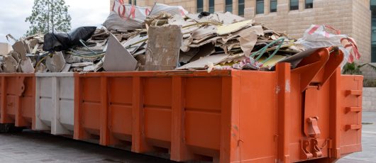 Large Orange Dumpster Full of Traditionally Used Construction Materials