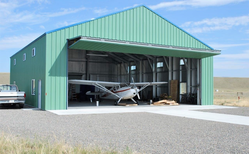Blue aircraft hangar that is housing a small personal aircraft.